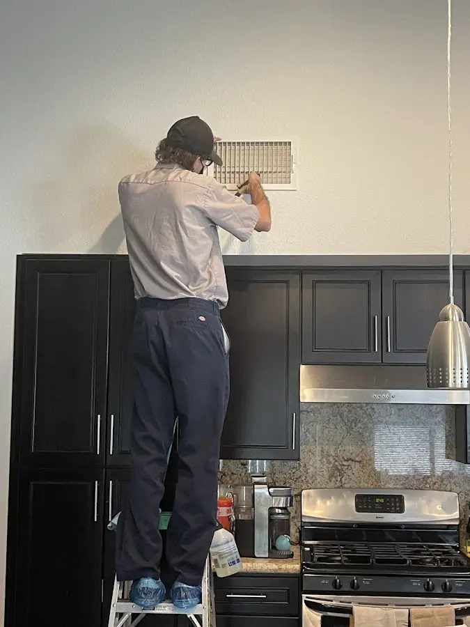 Technician inspecting an air vent during HVAC service in Catonsville